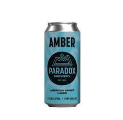 A single aluminum beer can for Paradox Brewery's Amber American Amber Lager, featuring a light blue and teal patterned design with a black circular logo, centered on a plain white background.