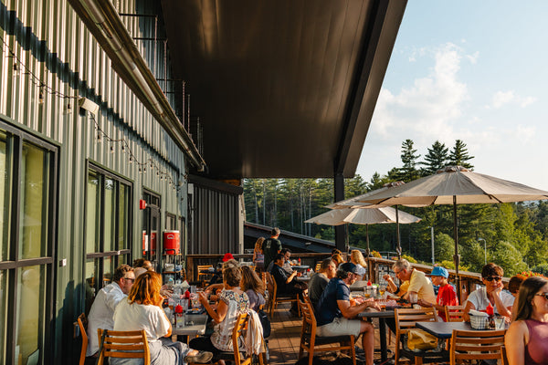 People dining outdoors at a restaurant with trees in the background at Paradox Brewery